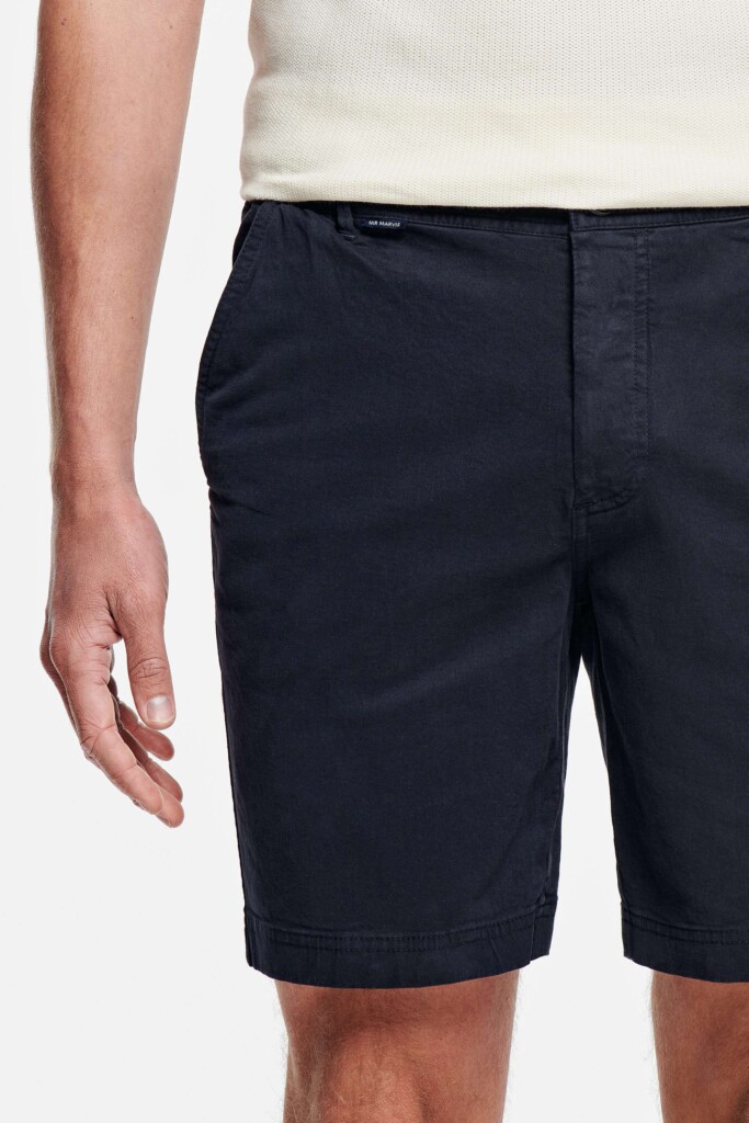 Zoom sur un short chino bleu marine de la marque Mr Marvis, porté. 