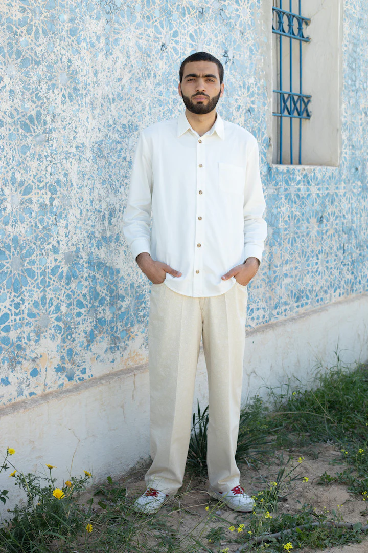 homme-habillé-en-blanc-devant-mur-bleu