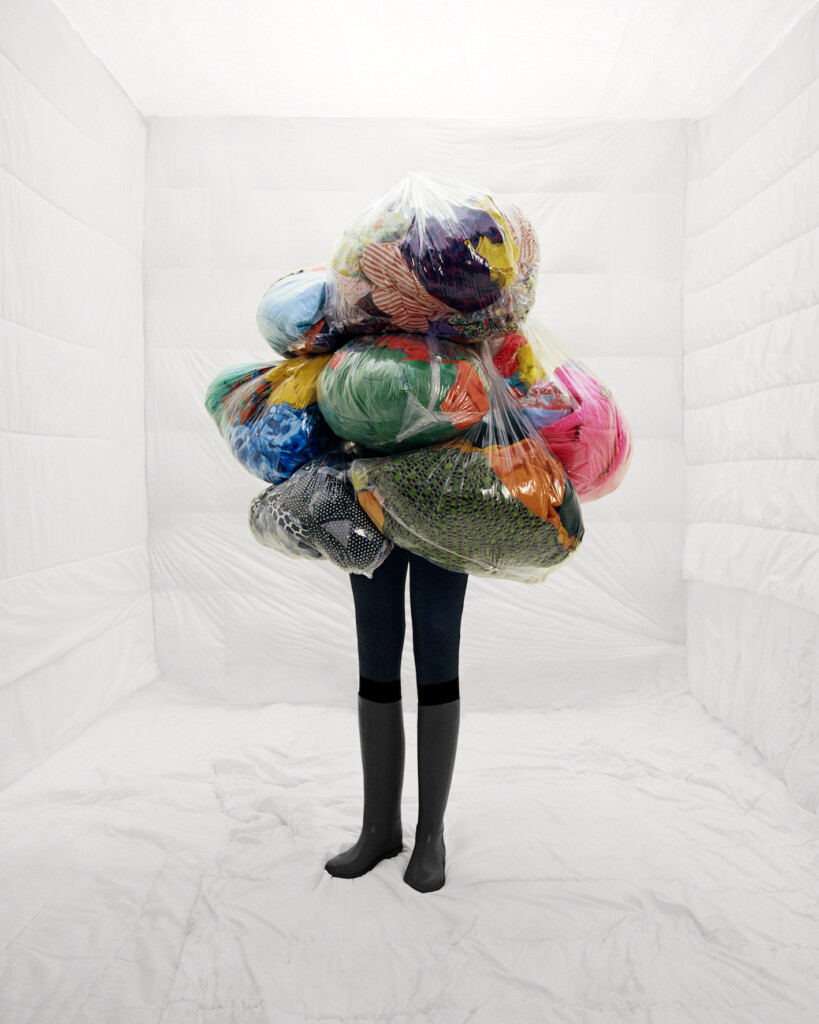 Une personne habillée de sacs poubelles contenant des vêtements usagés