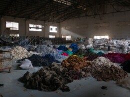 une usine de tri des textiles où on voit des vêtements triés, en piles, par couleurs