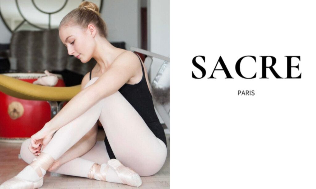Une jeune femme assise, elle porte une tenue de danseuse, un justaucorps de la marque Sacre Paris