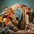 Une pile de vêtements de toutes les couleurs, en vrac sur un fond sombre.