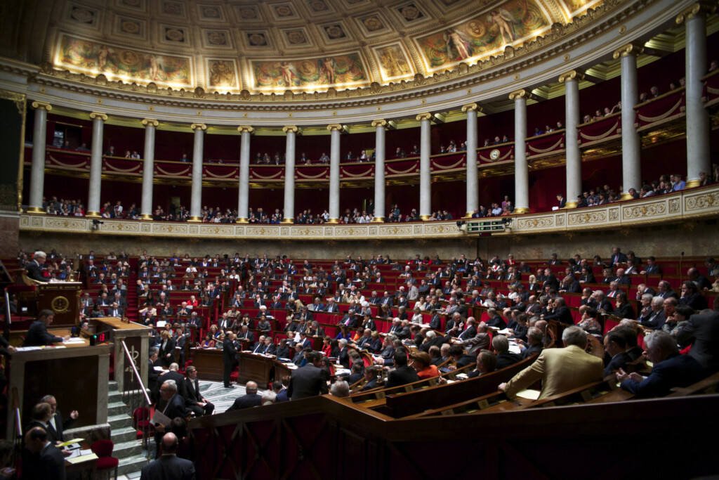 L'intérieur de l'Assemblée nationale en France. Les députés sont assis dans l'hémicycle.