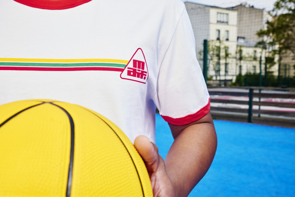 Un mannequin porte un t-shirt blanc à col rouge. Sur la poitrine, l’ancien logo de la MAIF. 