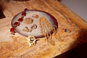 Une assiette en céramique sur laquelle sont disposés des bijoux en or et en pierres précieuses