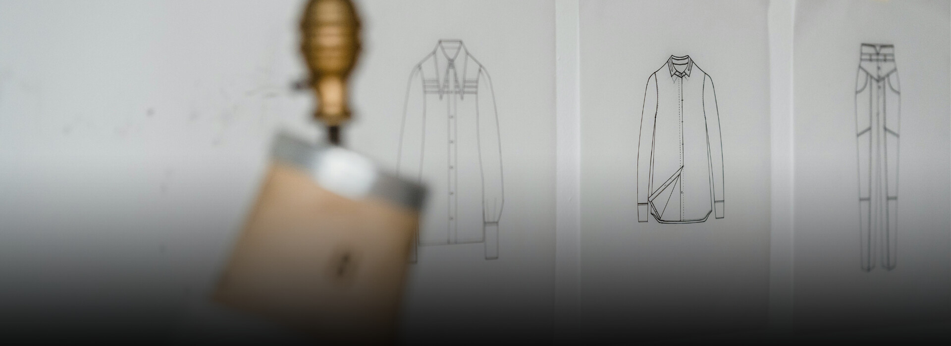 Banniere eco-concetion : un mannequin stockman dans un atelier avec, en fond, des croquis de vêtements