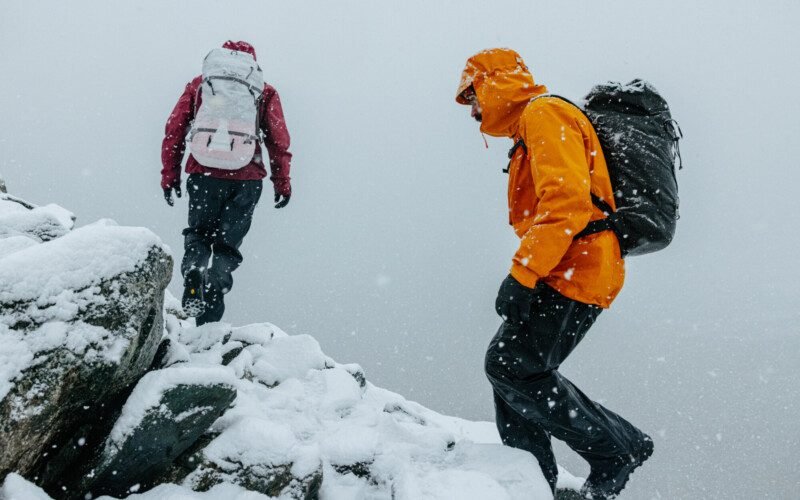 deux-personnes-escaladent-une-montagne-enneigee-habillees-en-arcteryx